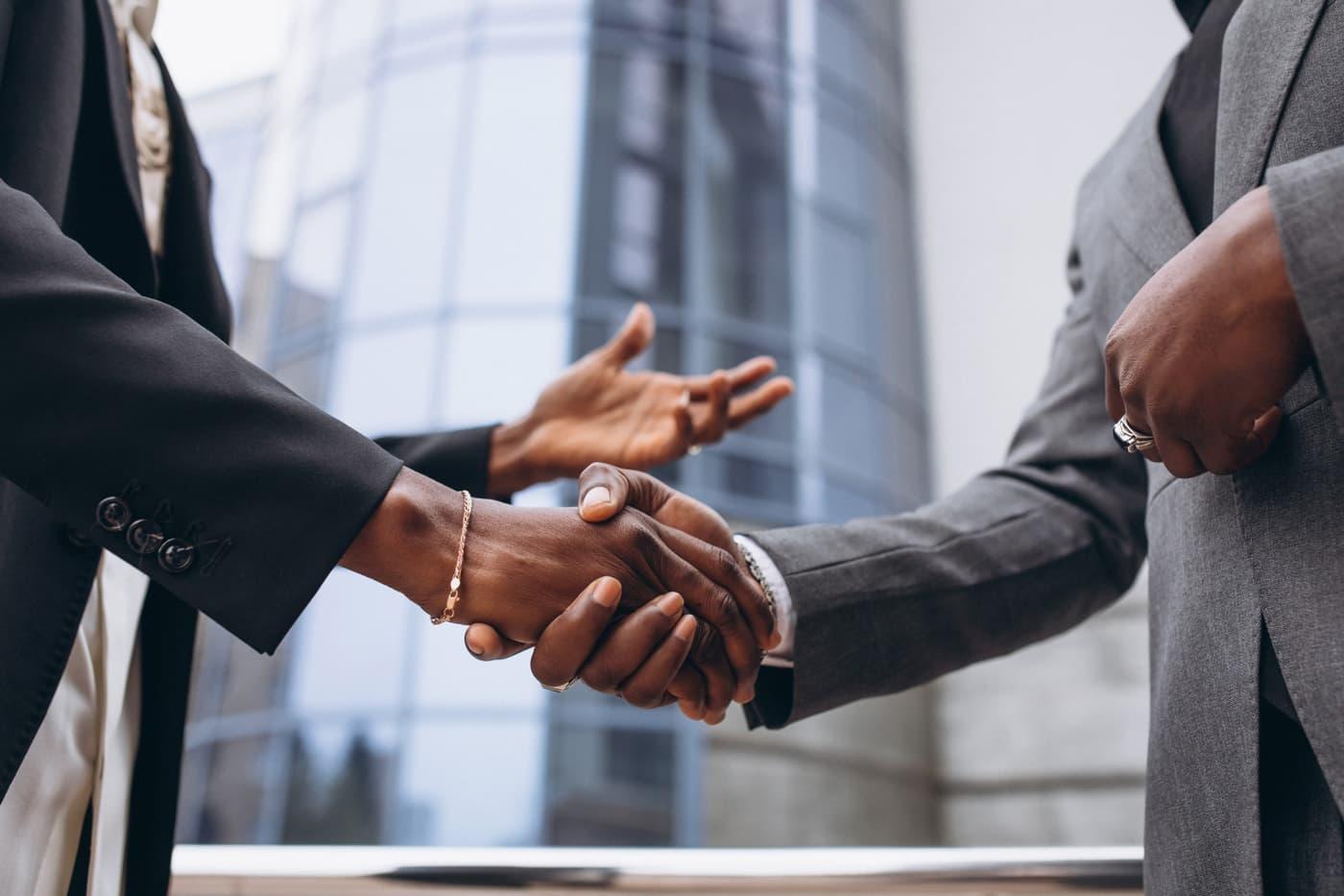 Two business people shaking hands in front of an office building