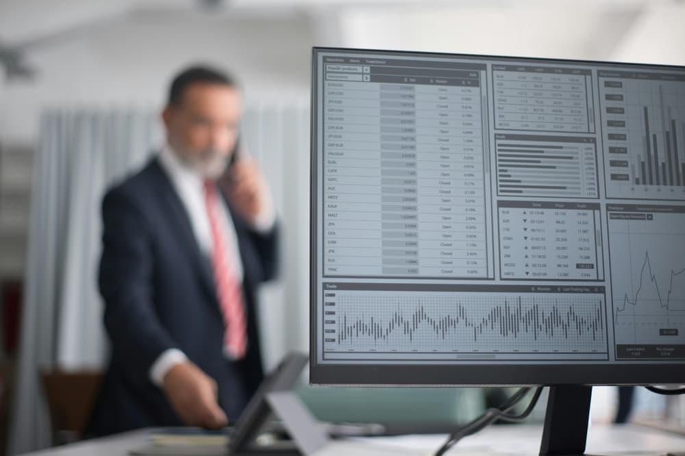 Businessman on a call in front of trading screens